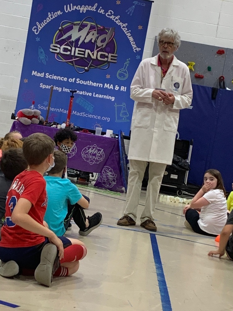 mad scientist standing with students sitting on the floor around him