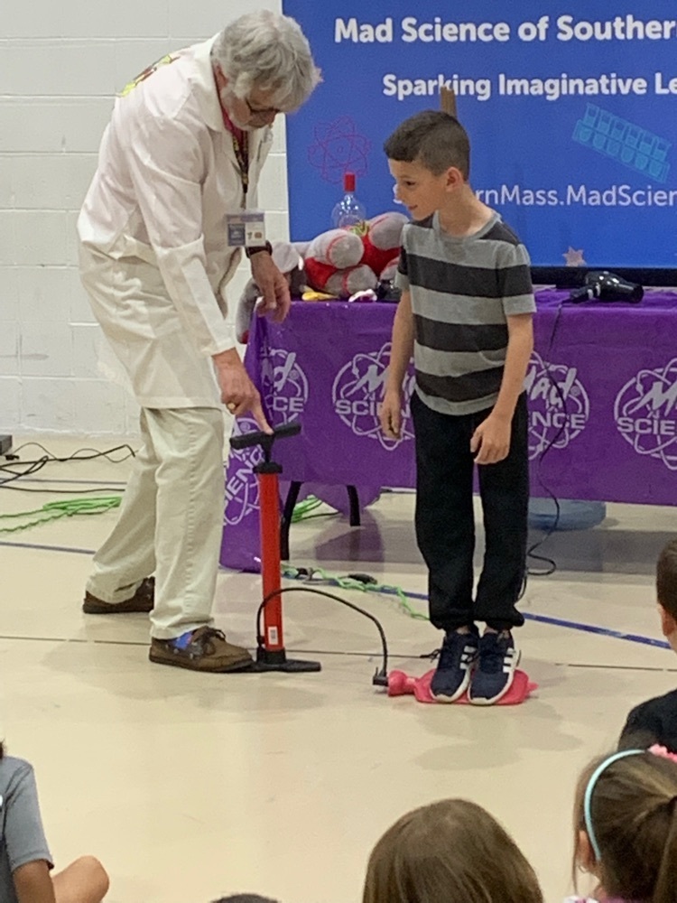 student standing on a balloon connected to an air pump with the mad scientist beside him