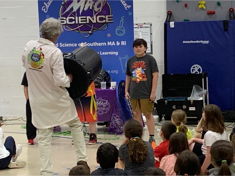 mad scientist holding a large trash can in front of a student standing up