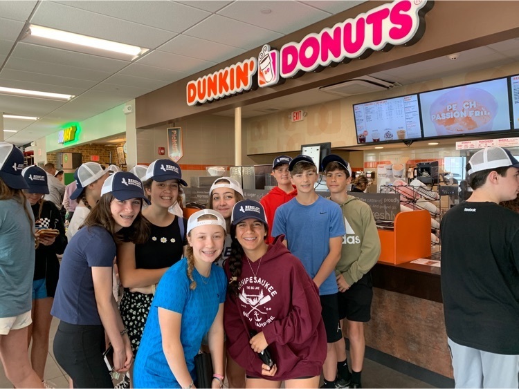 group of 8 students posing in front of a Dunkin coffee shop