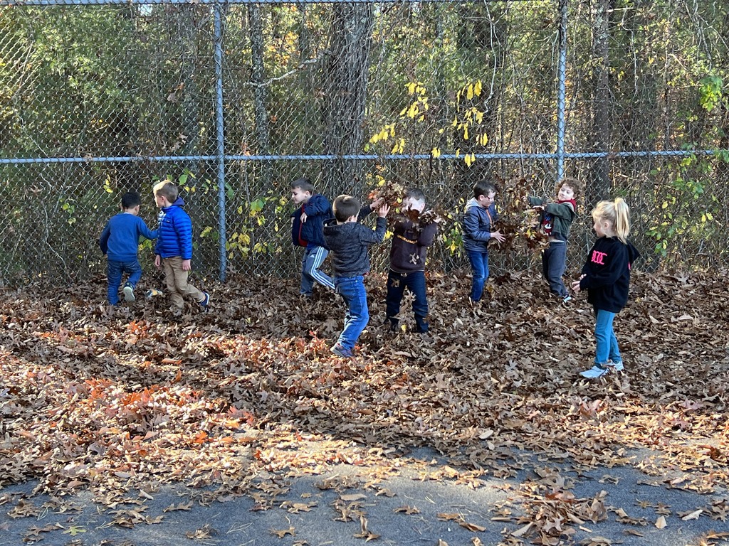 Kindergarten students playing in the leaves at recess